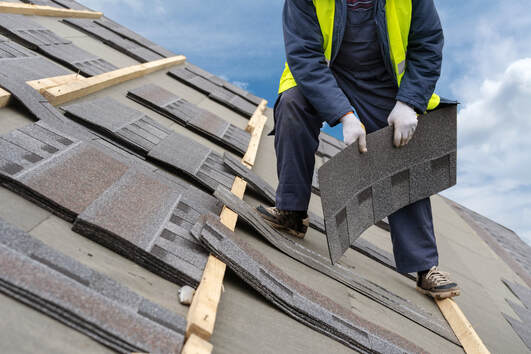 Worker installing roof shingles